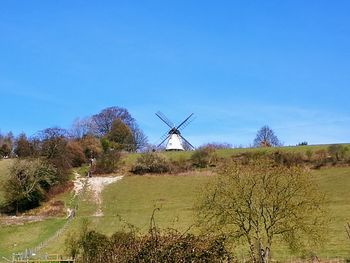 Windmill on farm against clear blue sky