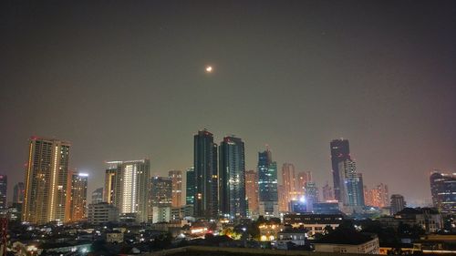 Illuminated cityscape against sky at night