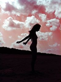 Silhouette woman standing on field against sky during sunset