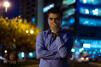 Portrait of young man in city street at night
