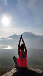 Woman doing yoga against mountains