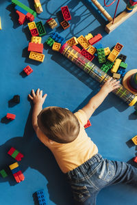 Rear view of baby boy playing with toys while lying on floor at home