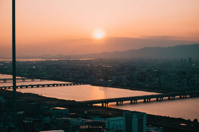 High angle view of river by buildings against sky during sunset