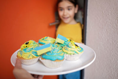 Ukrainian girl for whom neighbors brought cupcakes with cream in yellow and blue colors for brunch