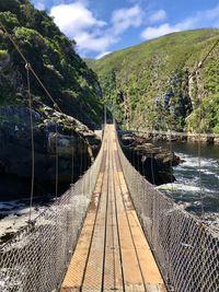 Footbridge over mountain against sky