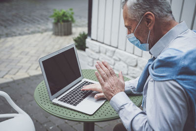 Midsection of man using mobile phone while sitting on table