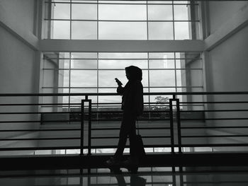 Side view of silhouette woman standing against railing in building