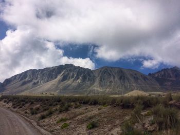 Scenic view of road by mountains against sky