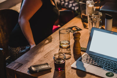 Laptop by pepper mill and drink on table