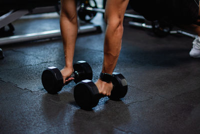 Low section of man holding dumbbell in gym