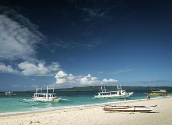 Sailboats moored on sea against sky