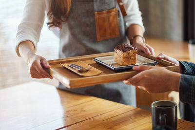 Midsection of woman serving bread in restaurant