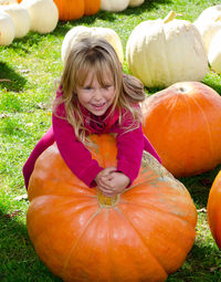 Little girl  tries to lift a  giant pumpkin, but it's too heavy to take home