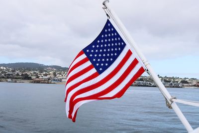 American flag on boat against cloudy sky