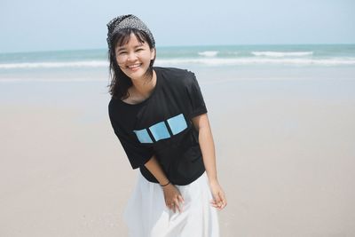 Portrait of young woman standing against sea against sky