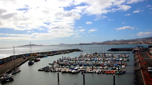 Boats moored at harbor against sky in city