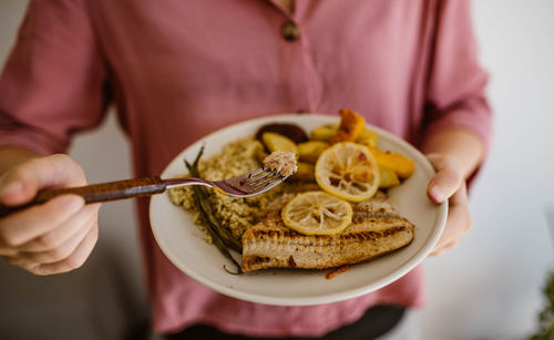 Midsection of woman holding food in plate