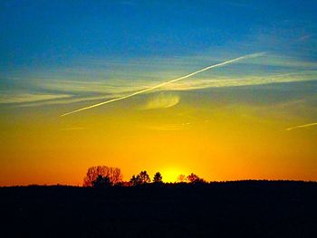 Silhouette landscape against dramatic sky during sunset