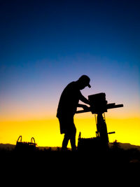 Silhouette man standing on field against sky during sunset