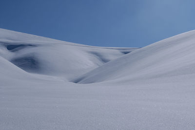 Snow covered land against blue sky