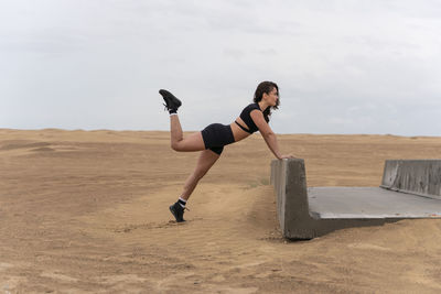 Full length of woman exercising on land against sky