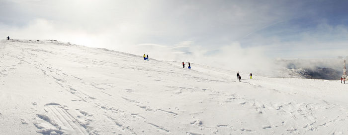 People skiing on snowcapped mountain against sky