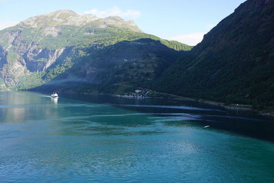 Scenic view of sea and mountains against blue sky