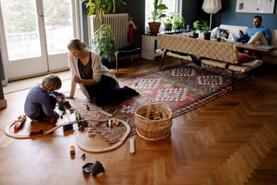 Mother and daughter playing with train set in living room at home