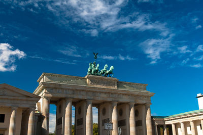 Low angle view of quadriga on brandenburg gate in city against blue sky