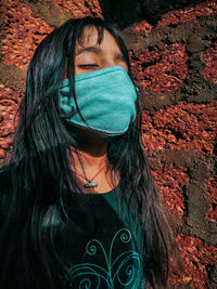 Portrait of young woman standing against brick wall