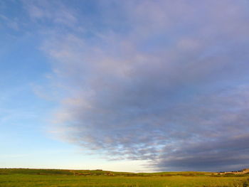 Scenic view of grassy field against cloudy sky