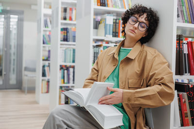 Portrait of young woman using digital tablet in library