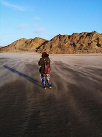 Rear view of woman standing at beach