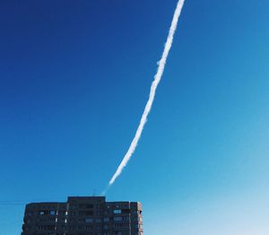 Low angle view of vapor trails against clear blue sky