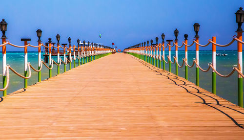 Footpath by sea against clear sky