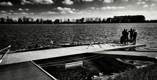 Pier over river against cloudy sky