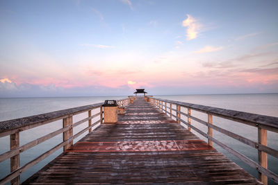 Pier over sea against sky during sunset