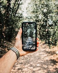 Midsection of person photographing with mobile phone