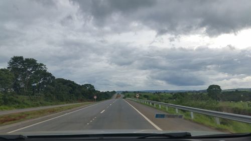 Country road against cloudy sky