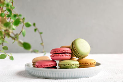 Colorful french macarons on pastel background. tasty cake macaroon of different colors in the plate.