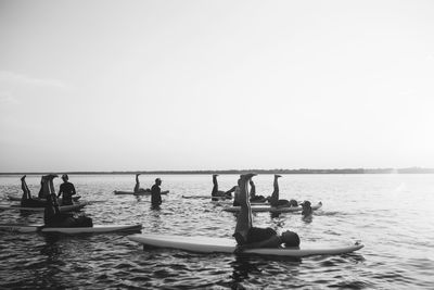 People in sea against clear sky