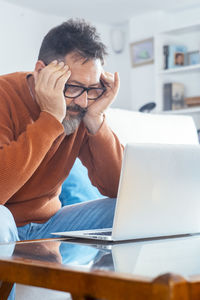 Side view of young woman using laptop at home