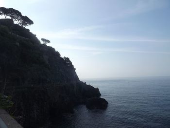 Scenic view of sea by cliff against sky