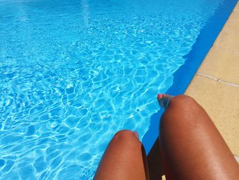 Low section of woman relaxing by swimming pool