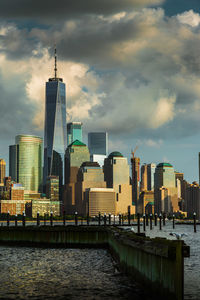 Modern buildings by river against sky in city