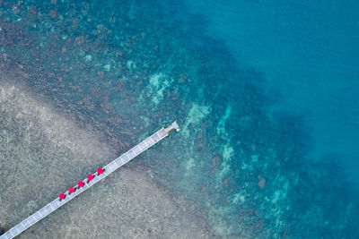 Bridge and red umbrella on the sea aerial view