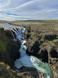 Scenic view of waterfall against sky