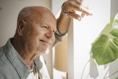 Smiling senior man day dreaming at home