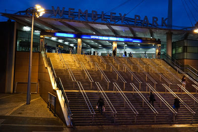 People waiting at illuminated railroad station at night