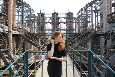 Portrait of young woman standing against railing